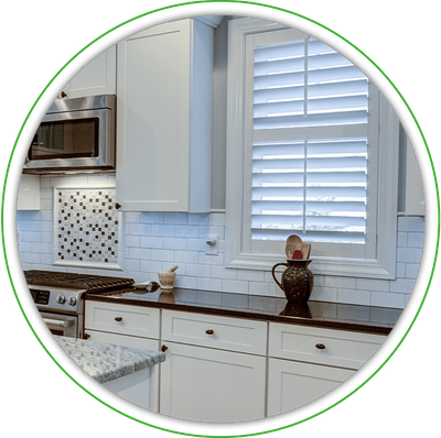 A kitchen window covered by white shutters