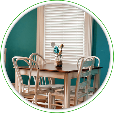 A dining room table placed in front of a window with the blinds lowered fully