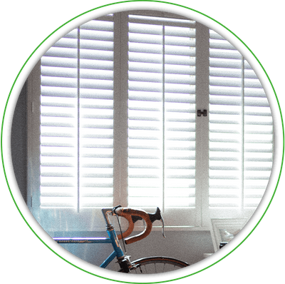 Large white interior shutters with a bike leaning against the wall