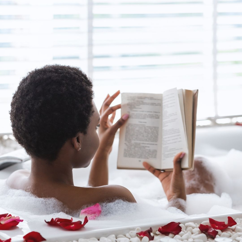 woman taking bath and reading book