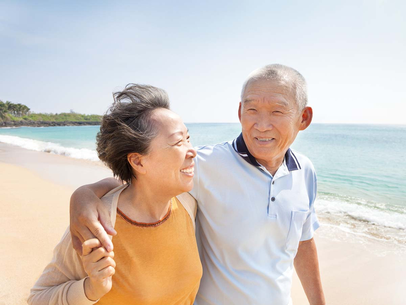 An elderly couple walking together on the beach