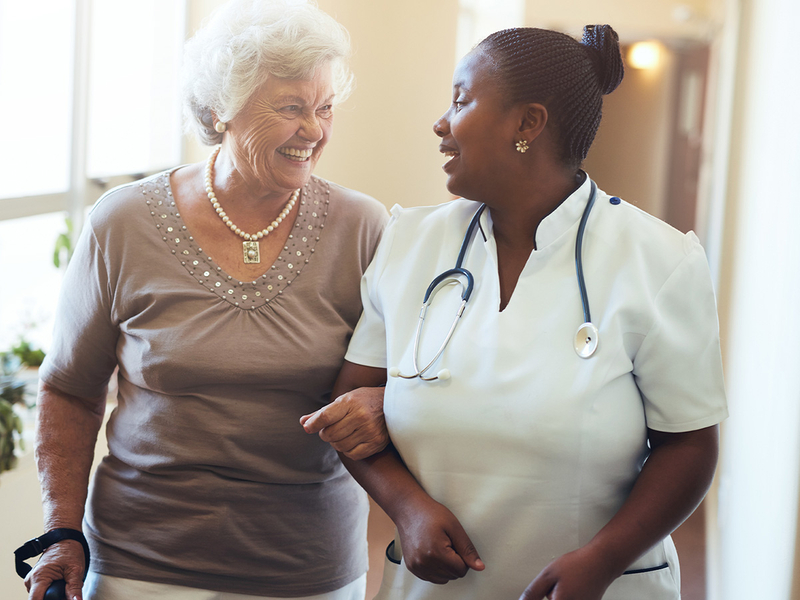 Senior women walking in the nursing home supported by a caregiver
