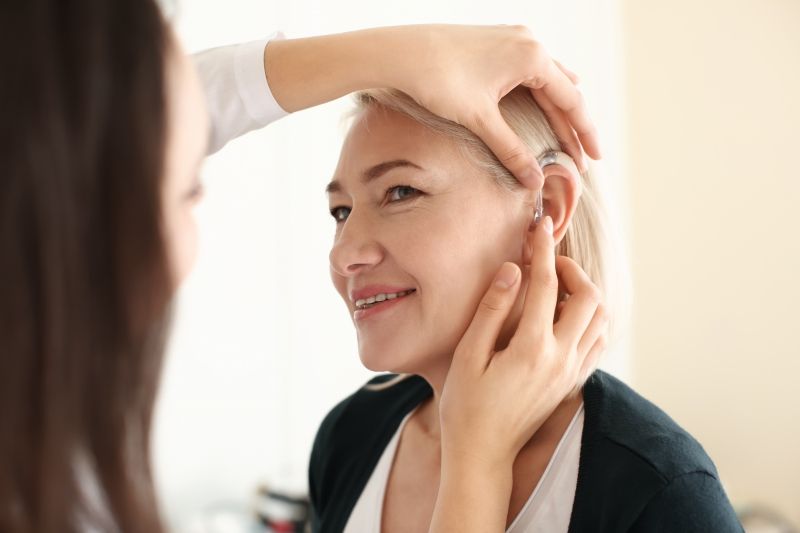 Otolaryngologist putting hearing aid in woman s ear.