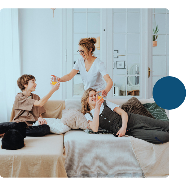 mom giving glasses of juice to kids on sofa SANTA BARBARA 3.png