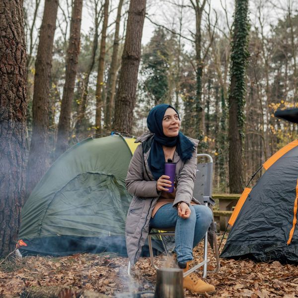 woman holds travel mug while sitting at camp CAFORA Partnership with Jo Coffee 3.jpg