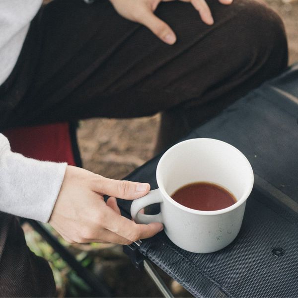 hand goes to pick up coffee mug on camp table CAFORA Partnership with Jo Coffee 2.jpg