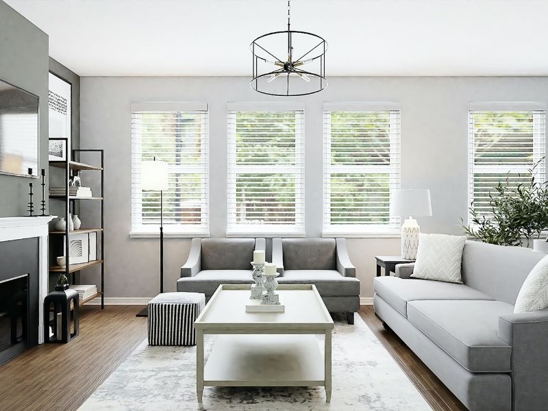 A contemporary living room seating arrangement consisting of a light grey sofa, two matching armchairs, and a white tiered coffee table on a grey patterned rug.
