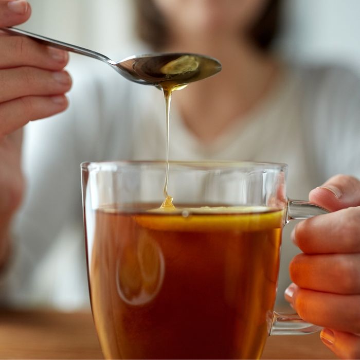 woman adding honey to her tea