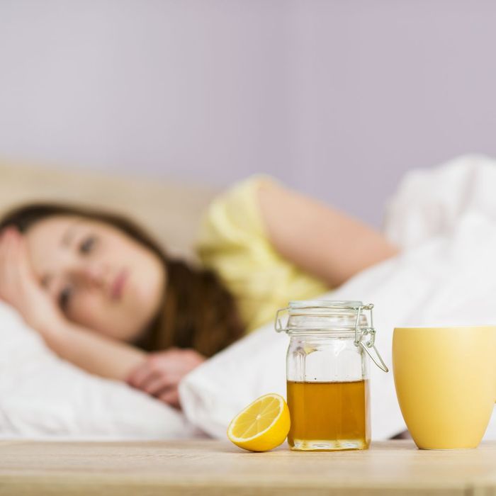 woman sick in bed with honey nearby