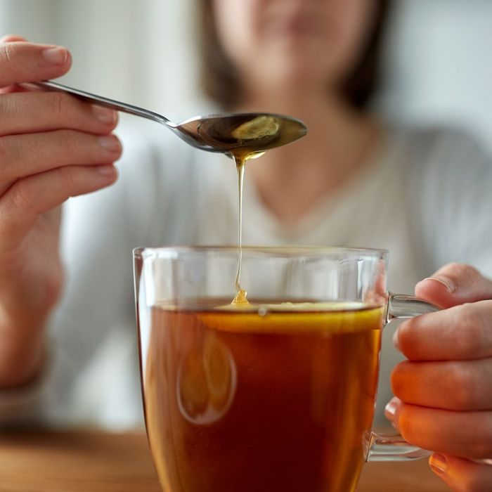 woman putting honey in tea