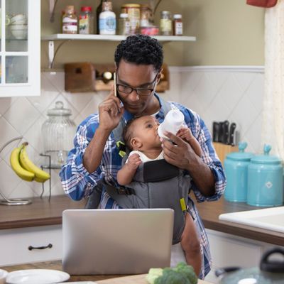 single father feeding baby while multitasking