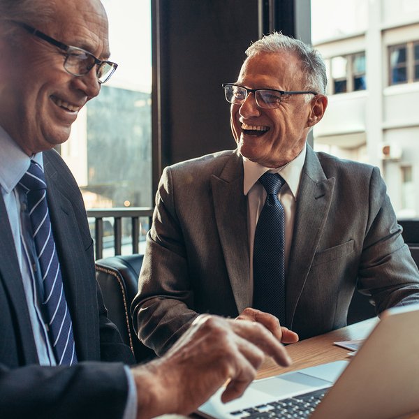 Two older businessmen at a meeting laughing with each other