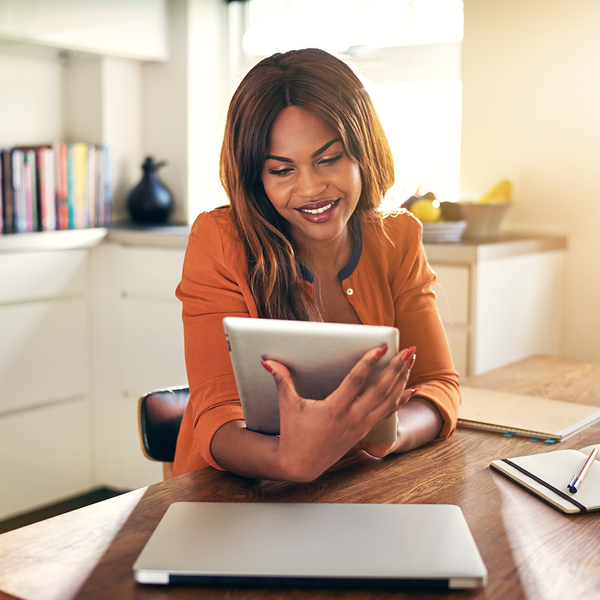 A woman smiling while looking at her tablet