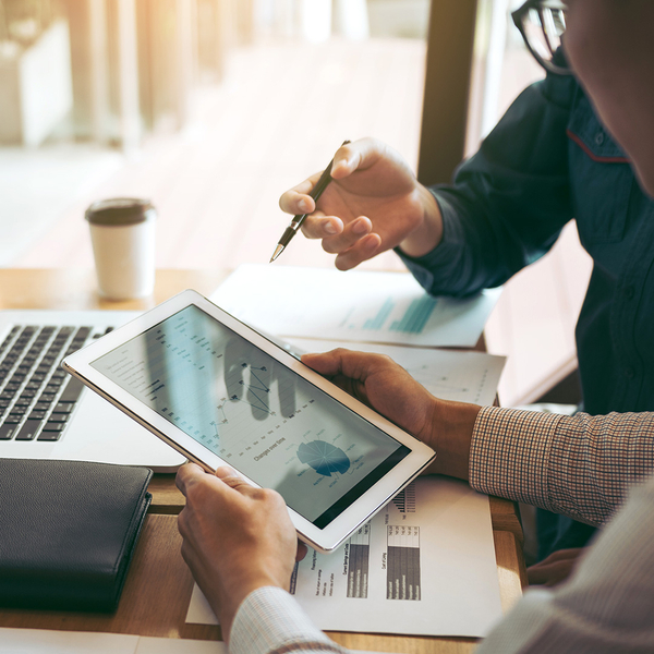 Two people looking at financial figures on a tablet