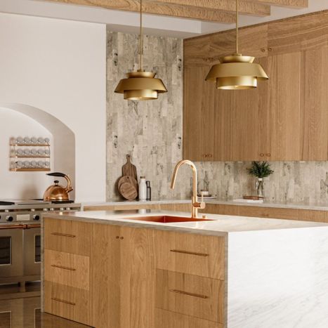 Two tiered gold pendant lights above a wood island.