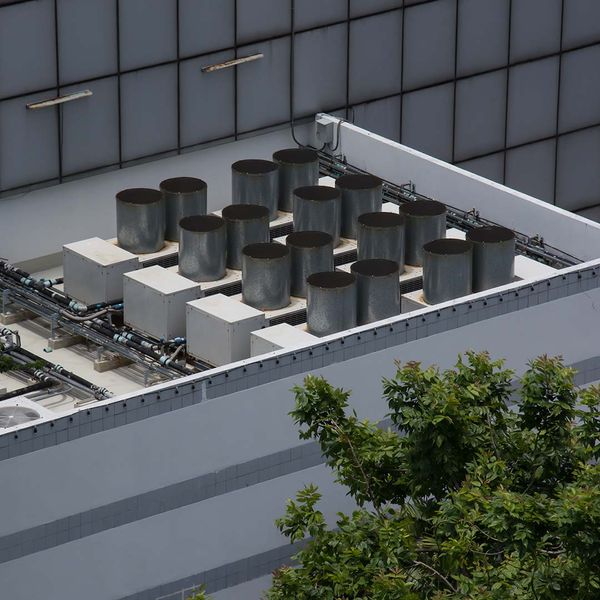 Commercial cooling HVAC air conditioner condenser on large commercial building rooftop.