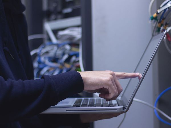 man with laptop inspecting data servers