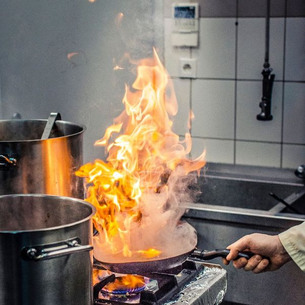 chef sautéing in pan with fire