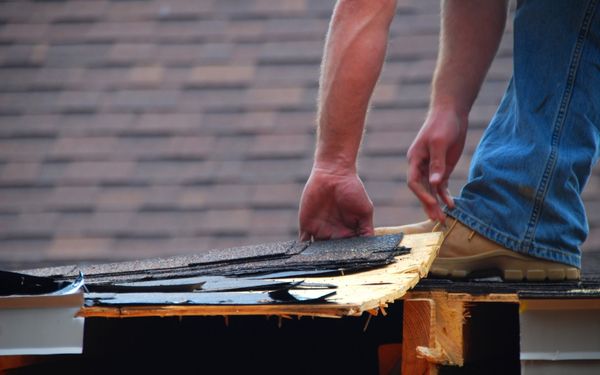 Roofer removing old shingles from a roof