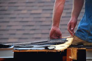 Roofer removing old shingles from a roof