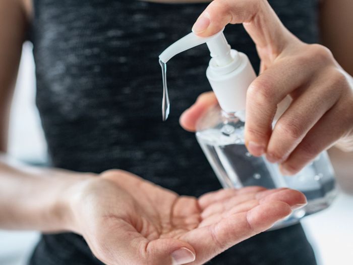 Image of a healthy woman squirting sanitizer into her hand