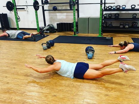 Woman doing supermans with gym classmates.