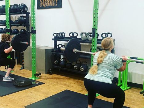 Women performing squats in a gym class.