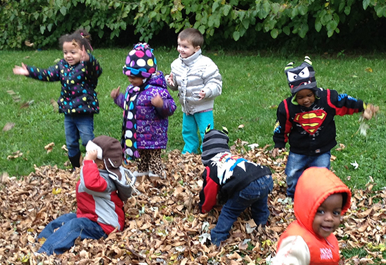 Children playing in a pile of leaves in the fall