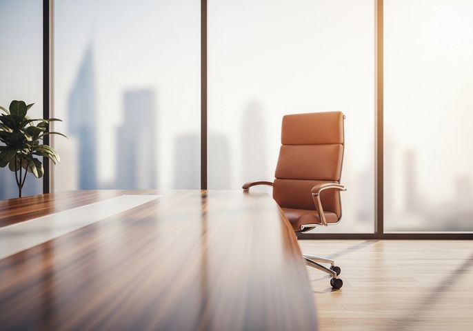 Empty executive leather chair at polished boardroom table in sunlight.