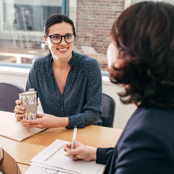 A woman smiling at her financial advisor while they speak in a meeting