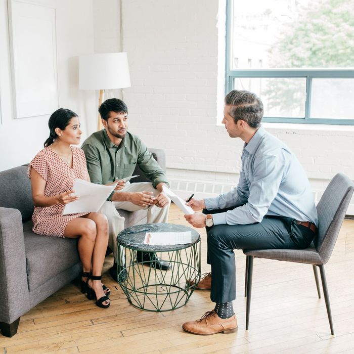 A financial advisor sitting in a living room speaking with his clients