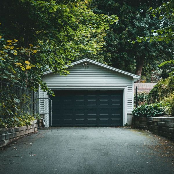 A garage door on a standalone garage with an asphalt driveway