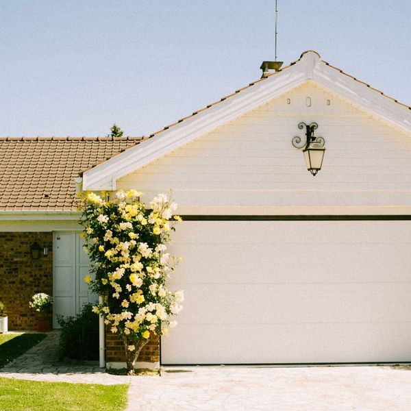The garage door of a home with a lovely rose bush next to it