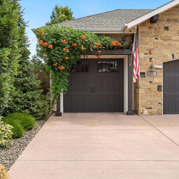 A well appointed garage door with a nice flower bush above it