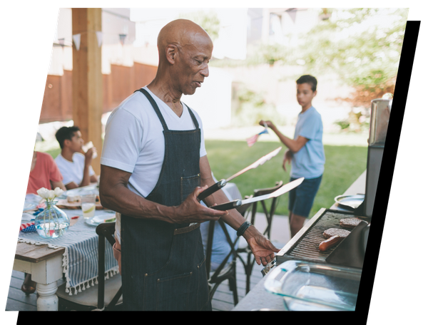 older man grilling on patio with family older man grilling on patio with family