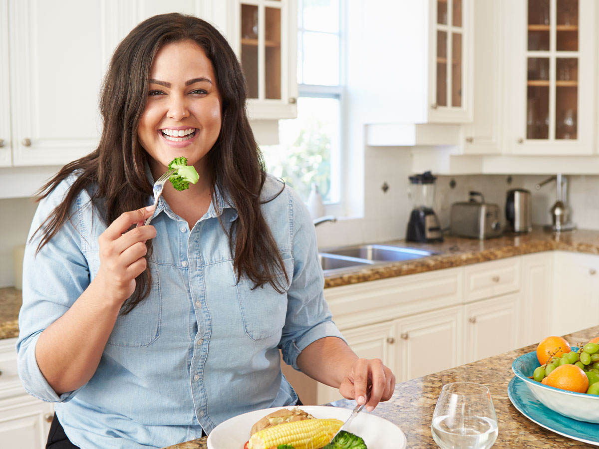 a woman eating broccoli