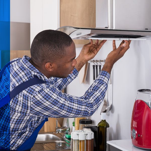 Man installing an oven hood in a nice kitchen