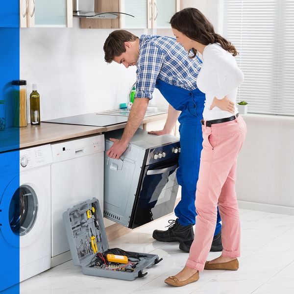 A repairman working on an appliance while the homeowner watches