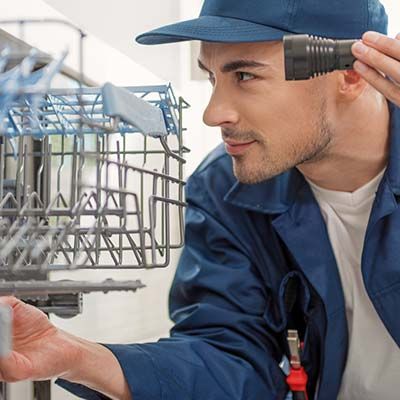 dishwasher repair technician using flashlight to look into dishwasher