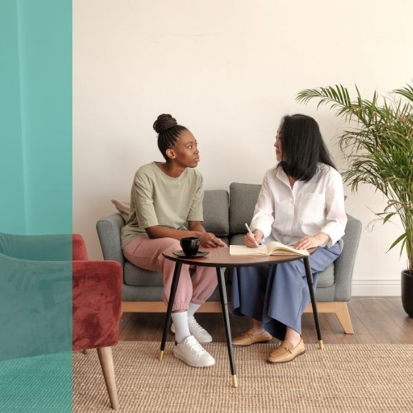 A therapist and young patient talk on a couch