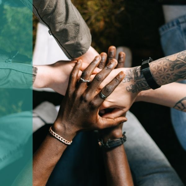 A diverse group puts their hands together in a huddle