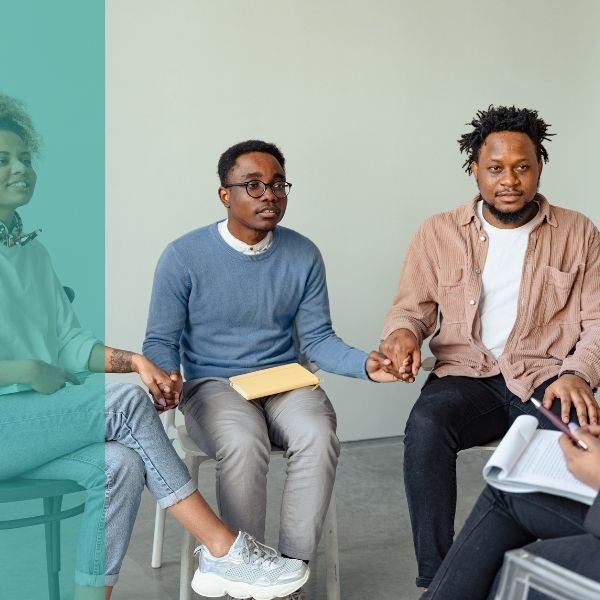 A group hold's hands while sitting in chairs in a circle