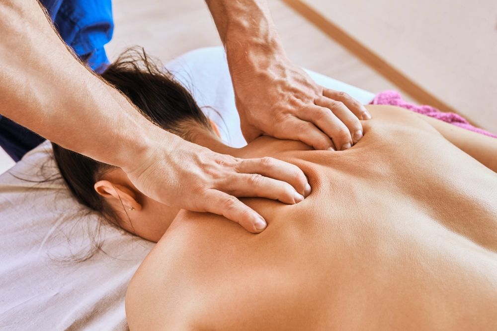 masseuse’s hands dig into a patient’s back during a deep tissue massage