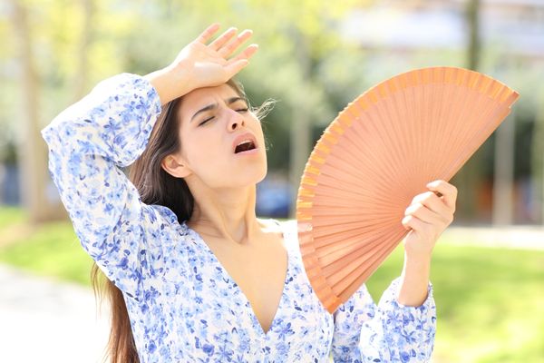 Woman fanning herself outside on a hot day in Dallas, Texas