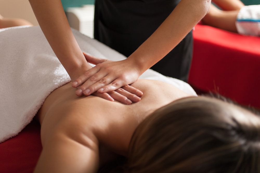 hands glide along a woman’s back as part of a Swedish Massage
