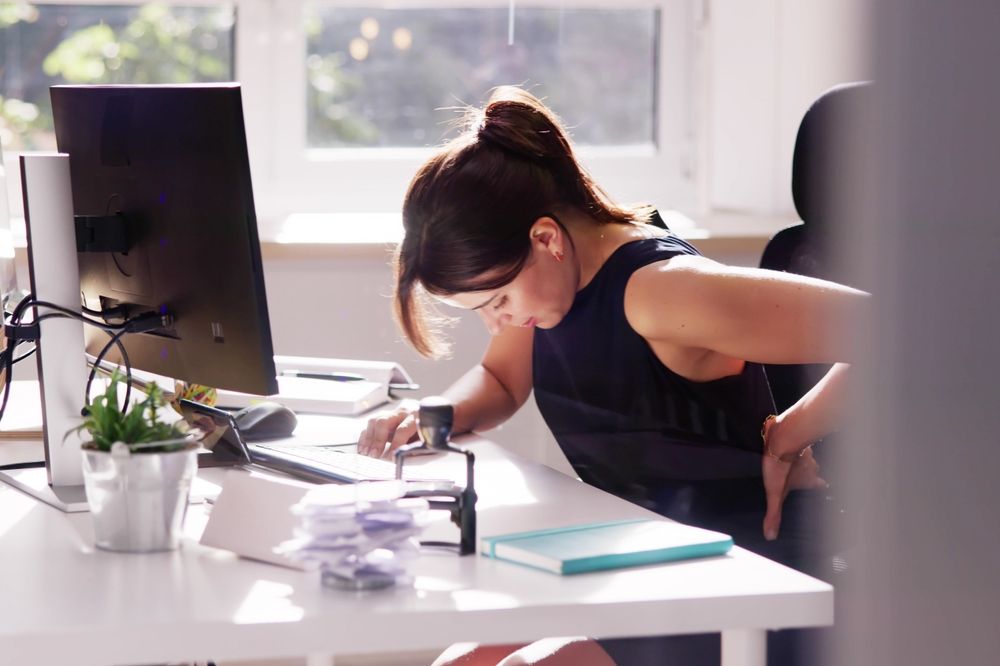A woman experiencing back pain from bad posture