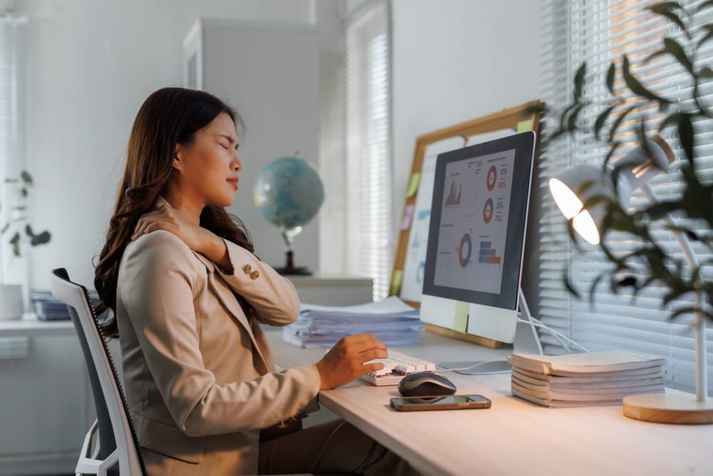 A woman struggling with neck pain while doing office work