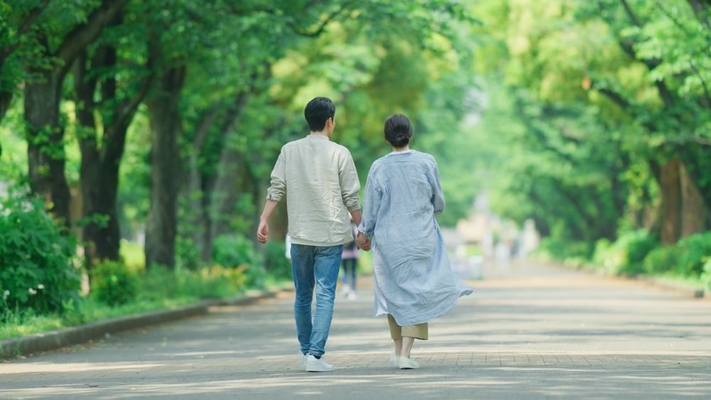couple holds hands while walking through a park
