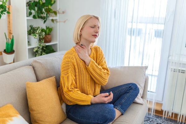 Woman holding her sore shoulder, the kind of pain deep tissue massage therapy can ease