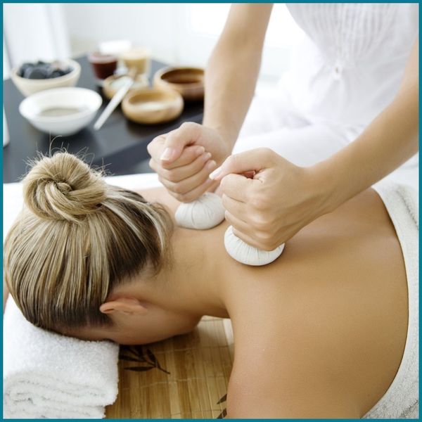 woman having warm clothes applied to base of neck during massage